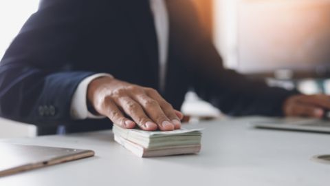 Man with hand on a pile of cash