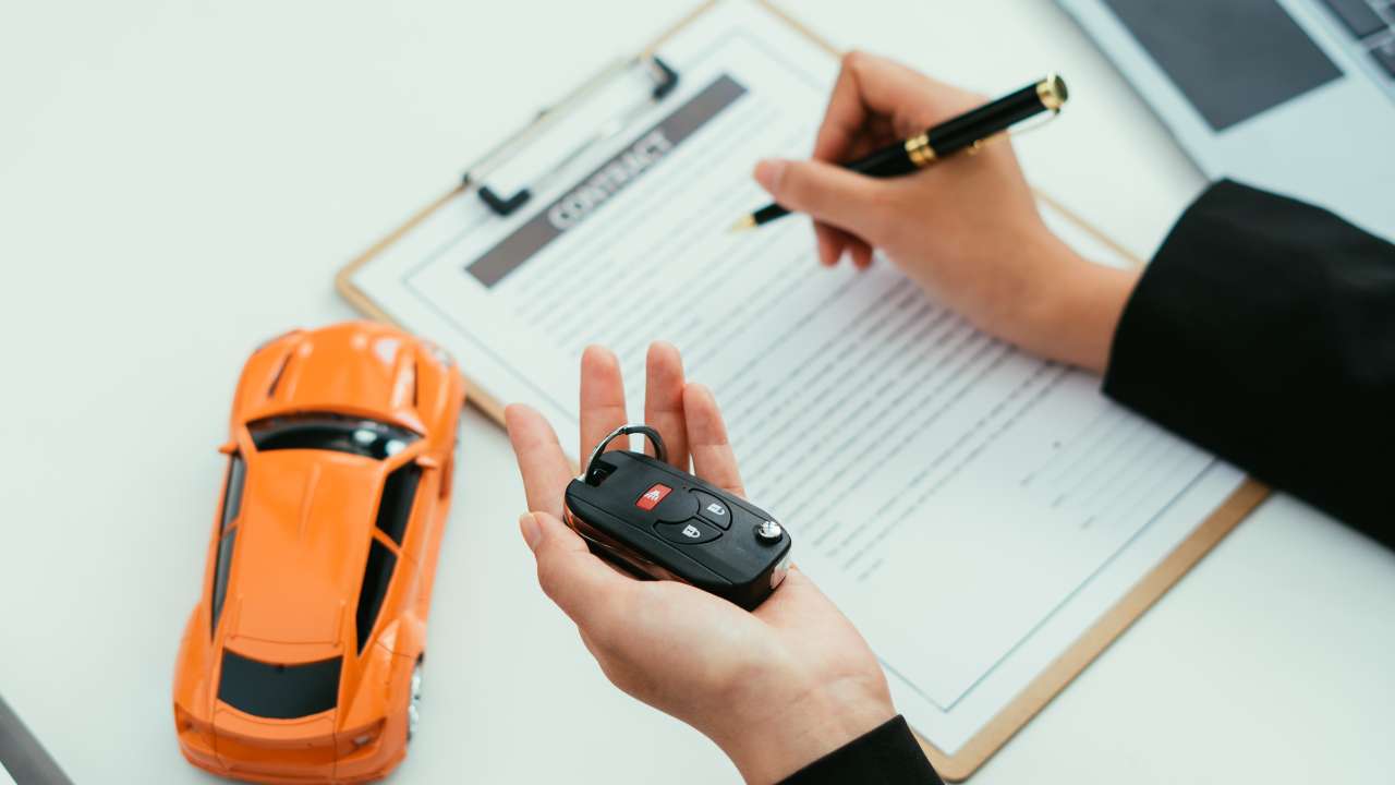 Person holding a car key whilst signing a contract