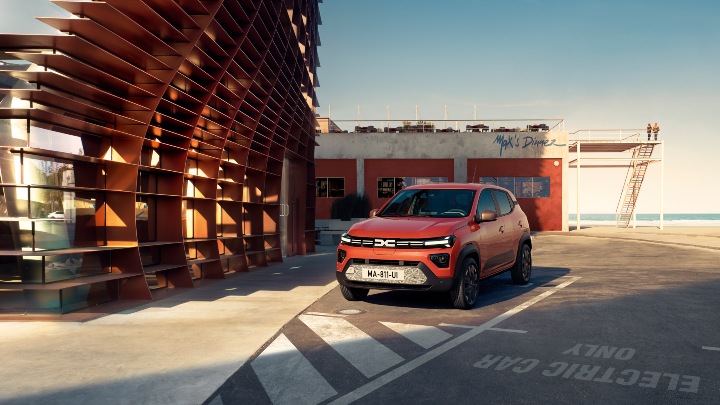Dacia Spring orange parked near office building