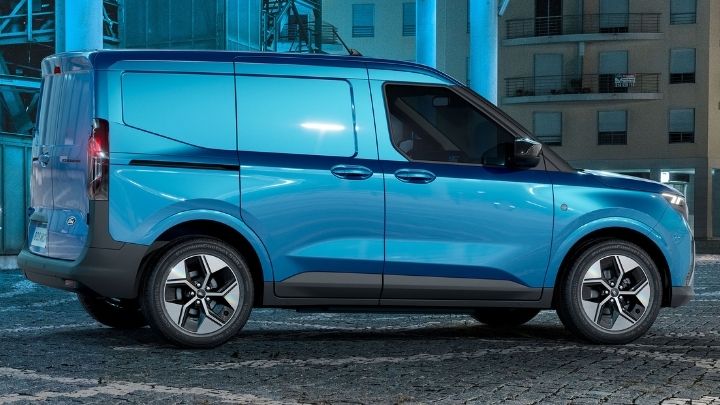 Silver Ford E-Transit Courier with the back doors open and a man carrying a box to the boot