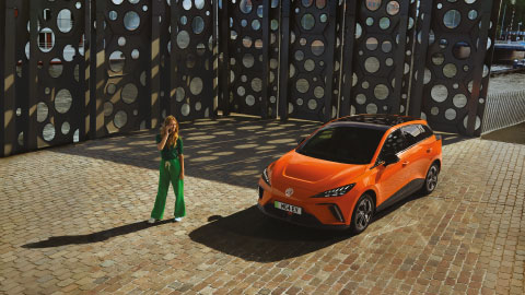 Woman Standing In Front of Orange MG4 EV