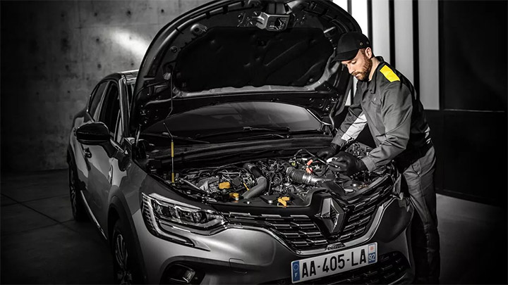 Young technician in overalls servicing a grey Renault Arkana